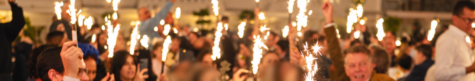 Bengalas encendidas entre los invitados durante una cena de celebración